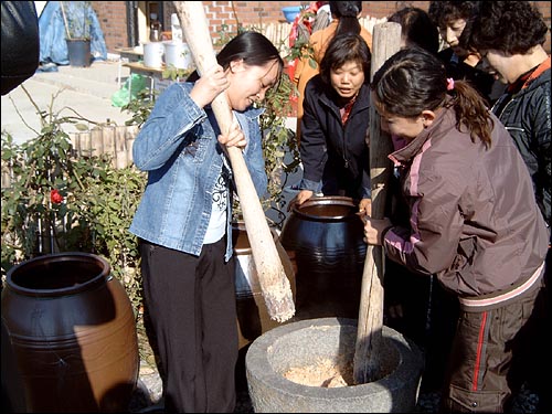 장 담그기 체험 행사에서 절구에 들어있는 콩을 빻고 있는 외국여성들 